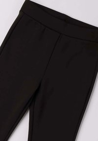 Zwarte leggings met een brede, gladde tailleband. Gemaakt van rekbaar materiaal, met een strakke vormgeving en zonder zichtbare naden of patronen.