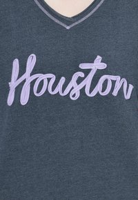 T-shirt grigio a collo a V con ricamo in testo viola "Houston" con finitura texturizzata e cuciture a contrasto lungo il colletto.