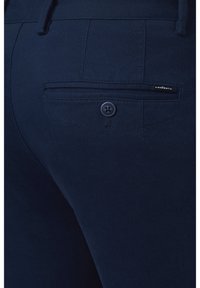 Granatowe spodnie wykonane z teksturowanej tkaniny, z tylną kieszenią z zapięciem na guzik i metką z logo.