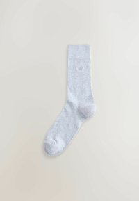 Világosszürke zokni puha anyagból, bordázott szegéllyel. Oldalán kis, diszkrét logóval és sima textúrával rendelkezik. Klasszikus kialakítás.