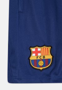 Námořnický sportovní dres s vyšívaným znakem FC Barcelona, červenými a žlutými pruhy, bílým křížem a prvky v modro-červených pruzích.