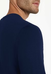 Marineblaue Baumwoll-T-Shirt mit Rundhalsausschnitt, kurzen Ärmeln, glatter Textur und taillierter Silhouette. Minimalistisches Design, keine sichtbaren Muster.