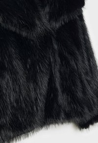 Black faux fur fabric featuring a soft, dense texture with varying lengths of fur. Slight sheen with minimal stitching details visible.