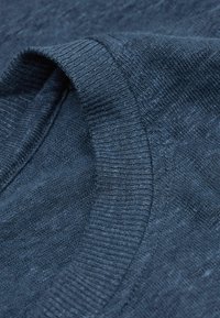 Tmavě modrá pletenina s žebrovaným kulatým výstřihem a hladkým povrchem. Tkanina má jemnou variaci v barvě.