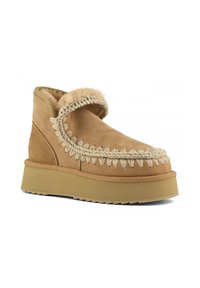 Stivaletto in suede marrone con una soffice fodera in pelliccia, cuciture decorative intrecciate e una suola in gomma di colore chiaro. Forma piatta e punta arrotondata.