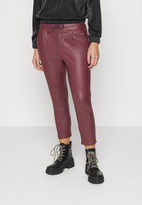 Mörkröda fusk lädercroppade byxor med dragsko i midjan, sidofickor och texturerad yta, kombinerade med svarta snörade militärstövlar.