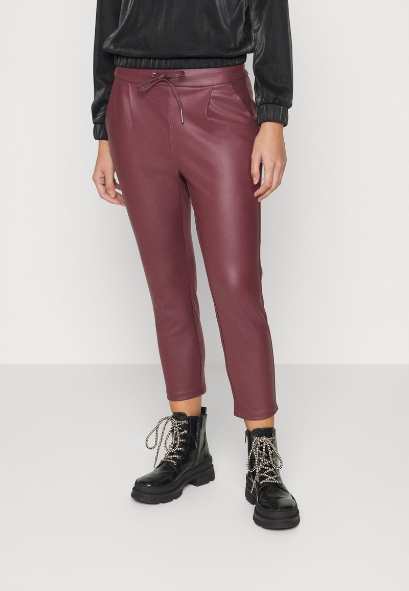 Mörkröda fusk lädercroppade byxor med dragsko i midjan, sidofickor och texturerad yta, kombinerade med svarta snörade militärstövlar.