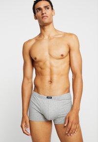 Grijze katoenen boxershorts met een elastische tailleband. Eenvoudig ontwerp, aansluitende pasvorm en zachte textuur. Model in neutrale pose.