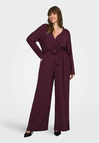 Bordeaux jumpsuit met lange mouwen, een V-hals, tailleceintuur en een wijde broekstijl, voorzien van een subtiele sprankeling in de textuur.