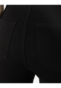 Zwarte denim jeans met een close-up van de achterkant, voorzien van twee zakken, zichtbare stiksels en een gladde textuur.