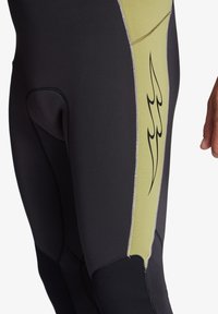 Black wetsuit featuring a textured lime green panel, black stitching, and a flame graphic. Smooth surface with reinforced knee areas.
