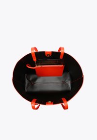 Czerwona skórzana torba tote z czarnym wnętrzem, dwiema krótkimi rączkami i małą kieszonką na zamek. Posiada dwie przegrody i złote akcenty hardware.