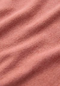 Tissu d'un corail doux avec une surface légèrement texturée. Le tissu semble lisse avec de fines lignes horizontales en relief.