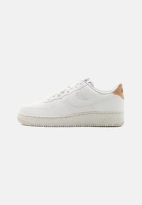 White sneaker with a smooth leather upper, textured accents, and a cork heel detail. Features a rubber sole with a distinct tread pattern.