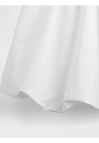 Robe en coton blanche avec un design fluide, une texture lisse et un ourlet arrondi, se drapant légèrement avec un éclat subtil.