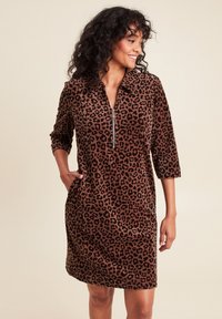 Bruine panterprint jurk gemaakt van zachte stof, met een ritskraag, driekwart mouwen en zijzakken voor extra functionaliteit.