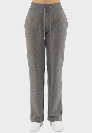 Donkergrijze sweatpants met trekkoord in de taille, gedragen met witte sneakers door een persoon die tegen een effen achtergrond staat.