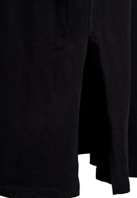 Sort bomulds t-shirt med korte ærmer, med rund hals og sideslids ved kanten. Glat tekstur, enkelt design uden mønstre.