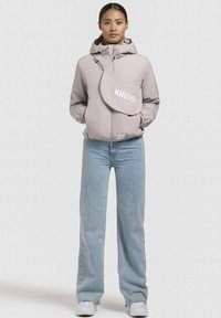 Light pink hooded jacket with zip closure, featuring a side bag with "KHUJO" logo, paired with wide-leg light blue jeans and white sneakers.