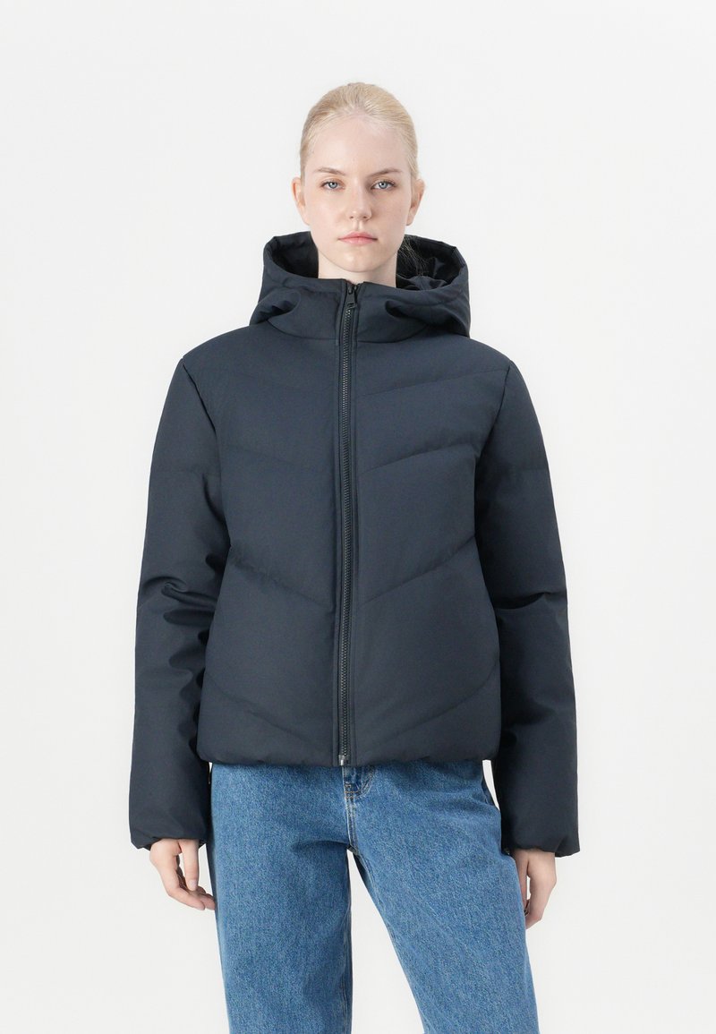 Puffer jacket in dark navy, featuring a hood, front zipper, and contrasting quilted pattern. Worn with light blue jeans.