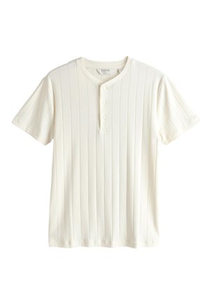 T-shirt henley blanc à manches courtes côtelé avec un col rond et trois boutons sur le devant, présenté sur fond blanc.