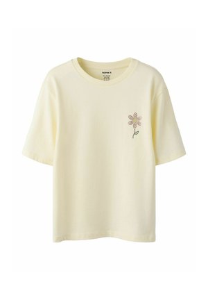 T-shirt jaune clair à manches courtes avec un petit motif de fleur en points sur la poitrine gauche et un col rond.