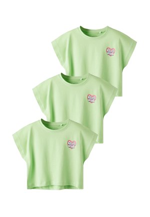 Three short-sleeve, cropped t-shirts in light green cotton, featuring a "Chill Out" heart logo on the left chest. Soft texture.