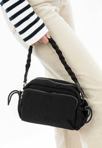 Borsa a tracolla in tessuto nero con una tracolla intrecciata, due scomparti con zip e un piccolo logo sulla parte anteriore. Presenta una texture liscia e un design minimalista.
