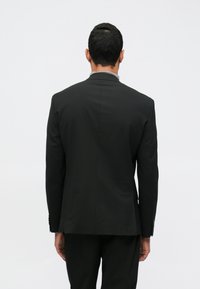 Μαύρο σακάκι με κομψή εφαρμογή, μονή σχισμή και δομημένους ώμους. Λείο ύφασμα με διακριτική γυαλάδα, χωρίς ορατά σχέδια.