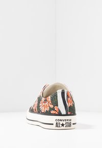 Baskets Converse à motif floral avec une base vert foncé, des fleurs orange, des rayures noires et une semelle en caoutchouc blanc. Logo au talon.