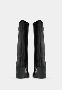 Pár černých kožených bot do poloviny lýtek s blokovým podpatkem, zadním zipem a detaily na kotnících, zobrazené zezadu na bílém pozadí.