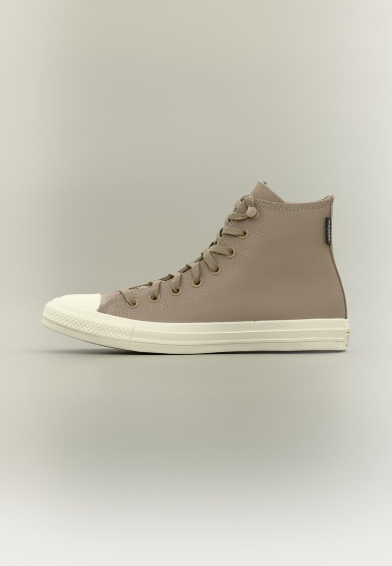 Beige high-top sneaker with textured upper, white rubber toe cap, and matching midsole. Features flat laces and metal eyelets.