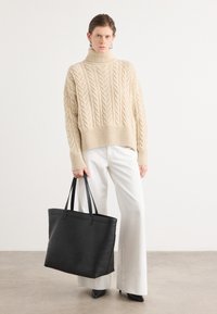 Paksu kaablikudega kudum beež turtleneck-sviiter, mis on kombineeritud valgete laiade pükste ning musta nahast käekotiga, millel on kahekordne käepide. Sujuv tekstuur ja kaasaegne disain.