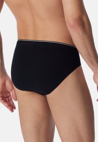Zwarte katoenen slips met een witte elastische tailleband. Glad texture, aansluitend design, en geen zichtbare patronen of versieringen.