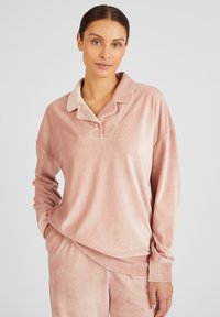 Top de felpa suave de color rosa, de manga larga, con cuello tipo polo, con tapeta de dos botones y puños de manga acanalados. Diseñado con un ajuste holgado.