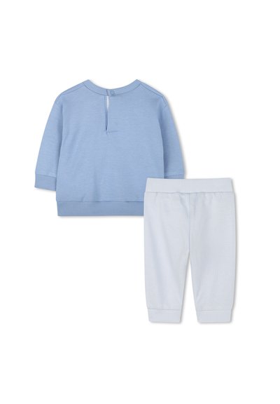 Lichtblauwe longsleeve top met geribbelde manchetten en knoopsluiting aan de achterkant, gecombineerd met bijpassende lichtblauwe broek met geribbelde enkelmanchetten.