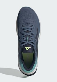 Scarpe da ginnastica sportive in rete blu navy con accenti neri, dettagli riflettenti e suola in menta chiara. Presentano un design strutturato con lacci e il logo sulla linguetta.