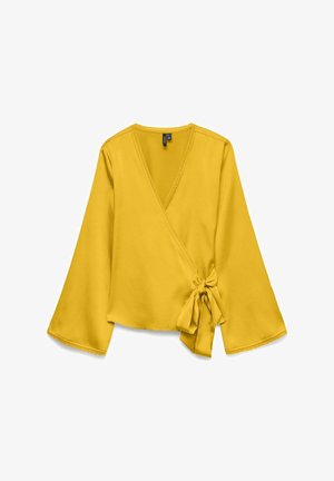 Geltonas užsegamas viršus su ilgomis, varpo formos rankovėmis, susirišimu ties liemeniu ir banguota apdaila aplink kaklą bei rankogalius. Lygi medžiagos tekstūra.