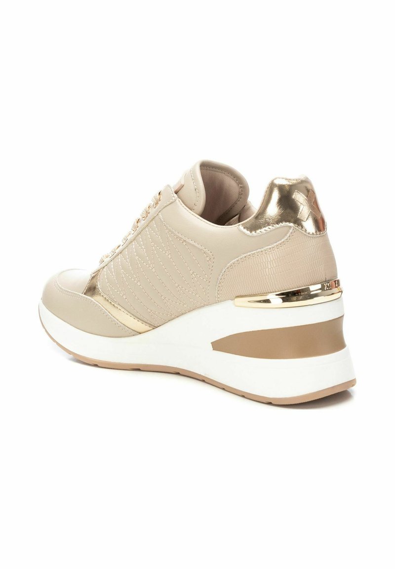 Sneaker beige con texture trapuntata, tacco e dettagli metallici, suola spessa bianca e oro, e design con punta rotonda.