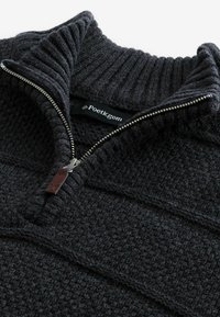 Pullover a maglia grigio scuro con collo alto e zip. Il tessuto testurizzato presenta strisce orizzontali; etichetta di marca visibile all'interno.