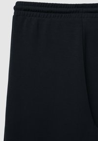 Marineblaue Jogginghosen aus einem weichen, glatten Stoff. Mit elastischem Bund und schmal zulaufendem Bein. Keine sichtbaren Taschen oder Muster.