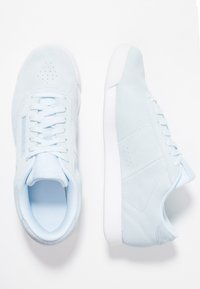 Baskets en daim bleu clair avec des semelles blanches, l'une montrée vue de dessus et l'autre de côté, sur un fond blanc.