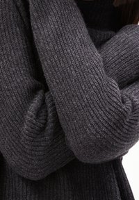 Pull en tricot gris foncé avec une texture côtelée ; les manches pliées créent une apparence chaleureuse, mettant en valeur les détails du fil doux et épais.
