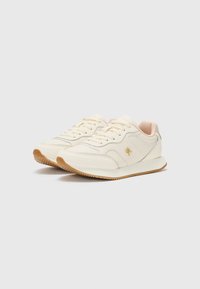 Hvite sneakers med en glatt læroverdel, en lys rosa innredning og en gummisåle med teksturerte detaljer og subtile sømmer.