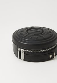 Round black leather bag with embossed logo detail, silver zipper closure, and two zipper pulls. Smooth texture with a structured shape.