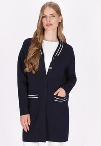 Marineblauer Cardigan mit weißen Streifen am Kragen und an den Taschen, ausgestattet mit einem Knopfverschluss und einem legeren Schnitt. Glatte Stricktextur.