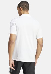 Weißes Polohemd mit kurzen Ärmeln aus glattem Stoff, das mit einem klassischen Kragen und einem schlanken Rückendesign mit subtilen Stickdetails versehen ist.