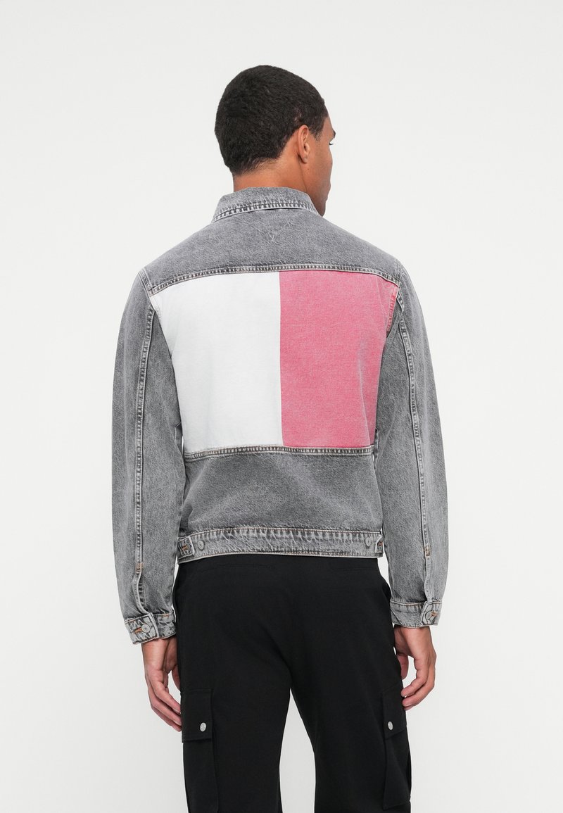 Graue Jeansjacke mit weißen und pinken Blockakzenten auf dem Rücken. Verfügt �über einen Kragen, knöpfbare Manschetten und ein entspanntes Design.