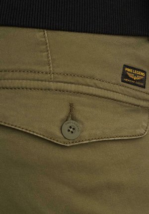 Detaljni posnetek žepa olivno zelenih hlač z zapiranjem na gumb in etiketo PME Legend nad žepom na črnem pasu.