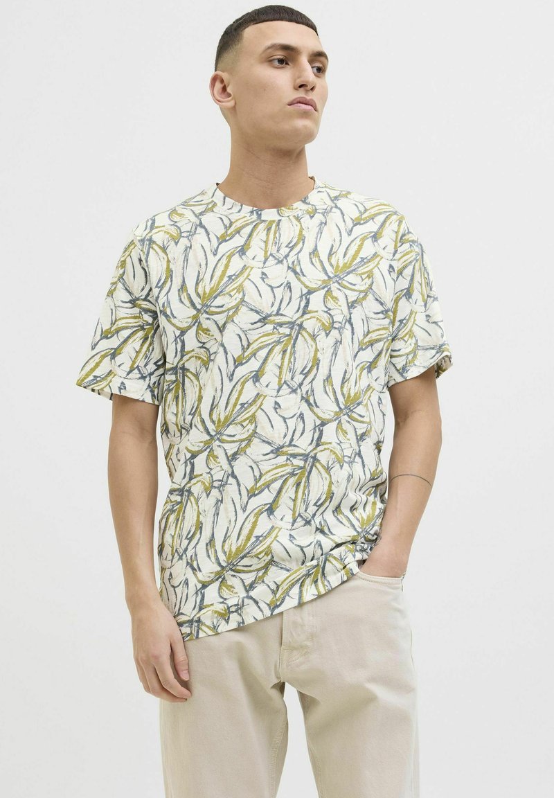 Tricou cu mânecă scurtă, confecționat dintr-un material ușor, având o bază bej cu un model de frunze verzi și albastre, decolteu rotund, croială lejeră.